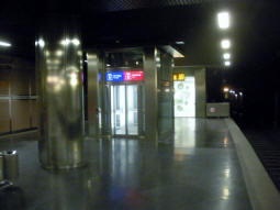 From the northbound island platform, a lift to exit and other platforms and behind that stairs down to the south- and eastbound platforms with access to the south-eastbound island platform too