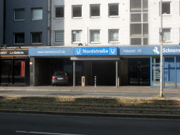 One of the entrances to the underground station seen from the other side of the road and tram tracks