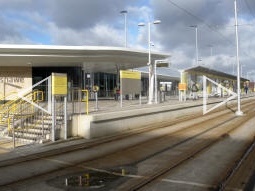 The bus station next to the platform for trams to Manchester, seen from the other side of the tracks (two photos automatically stitched together)