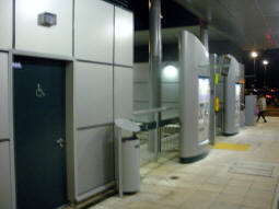 The disabled toilet, ticket machines and a tram and bus departure display at the end of the line at night
